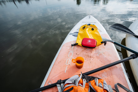 A paddle board, equipped with a prominently placed red first aid kit on it, is currently floating in the water, making it a perfect accessory for recreational activities on the lakeの写真素材