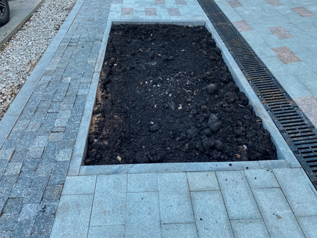 A meticulously filled trench is now prepared and ready for landscaping, and it is beautifully bordered by smoothly laid paved stones that enhance the appearance of a residential driveway areaの写真素材