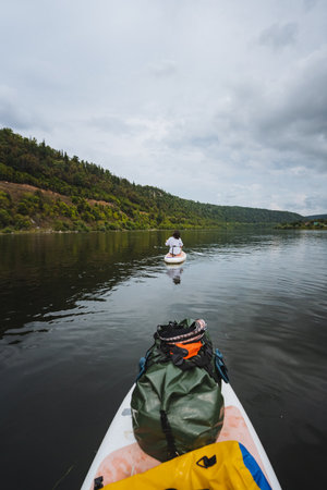 Embark on an exhilarating paddleboarding journey through serene waters, surrounded by vibrant greenery and captivating skies. Perfect for nature lovers and adventurous thrillseekers alikeの写真素材
