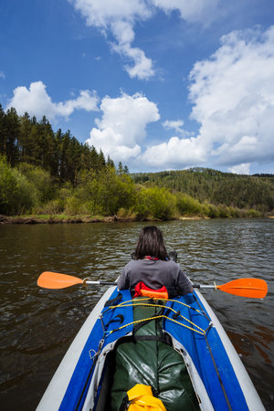 Experience tranquility while kayaking on a peaceful river, surrounded by greenery and a vast blue sky. This adventure invites nature lovers to explore and unwind in the great outdoorsの写真素材