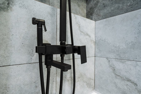 An elegant black shower faucet is beautifully set against contemporary gray wall tiles, showcasing a...