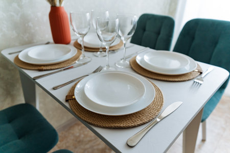 A beautifully set dining room table adorned with plates, glasses, and silverware meticulously...