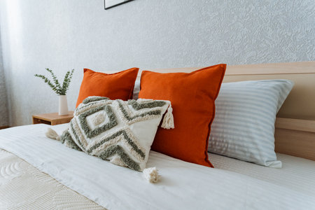 In a cozy and inviting bedroom, there is a plush bed adorned with an abundance of colorful pillows...