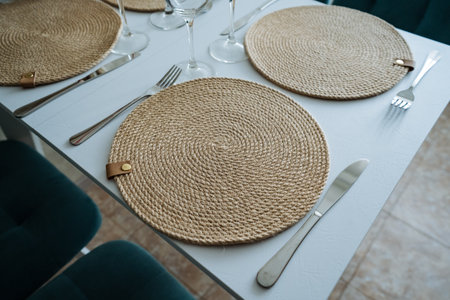 An elegantly set dining table with beautiful place mats and polished silverware creates a warm atmosphere, perfect for enjoying meals or hosting memorable gatherings with loved onesの写真素材