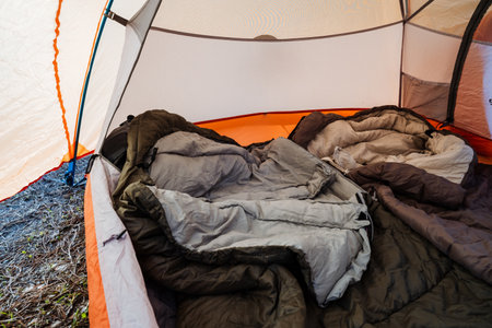 Imagine a cozy camping scene featuring two warm and comfortable sleeping bags nestled inside a spacious tent, ideal for creating unforgettable outdoor adventures and delightful nature escapesの写真素材