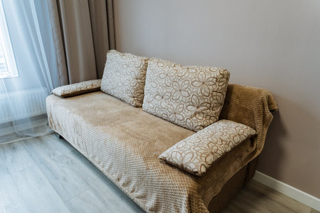 In a beautifully decorated living room, a modern brown couch is positioned by a large window,...
