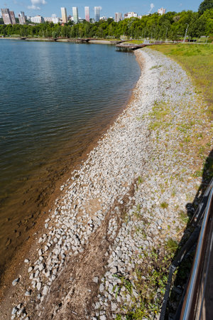 A rocky shoreline of a lake with a city in the background. High qualityの写真素材