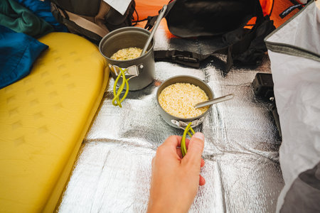 A person is gently holding a shiny spoon while it rests inside a bowl filled with food that looks...