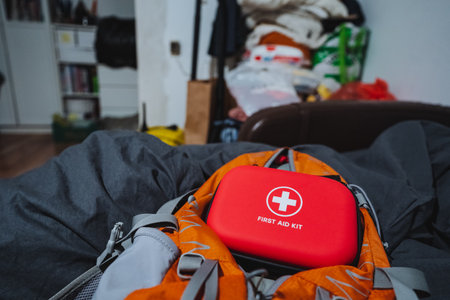 A bright red first aid kit is securely on an orange and gray backpack for easy access during...