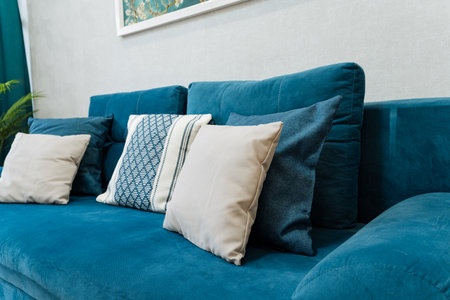 A stylish and chic blue sofa, tastefully adorned with various cushions, beautifully creating a warm...