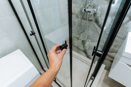 This sleek, modern shower features a stylish black knob, elegant glass doors, and a tiled background, making it both functional and visually appealing for various bathroom designsの写真素材