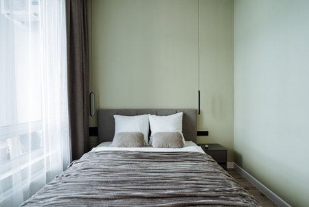 This minimalist bedroom, with soft bedding and a soothing color palette, uses natural light to create a relaxing spacea blend of comfort and modern elegance for unwinding after a busy dayの写真素材