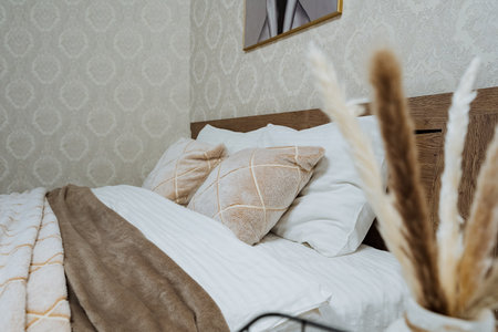 This fashionable bedroom showcases an array of soft, cozy bedding complemented by decorative pillows...