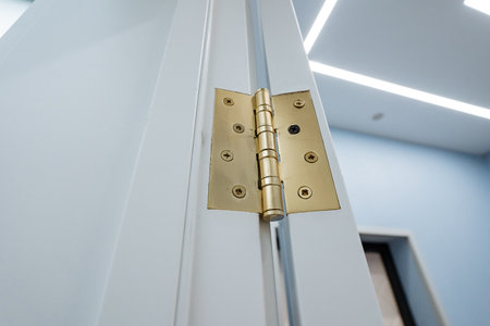 This image shows a detailed closeup of a beautifully crafted brass door hinge, highlighting its...