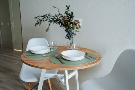 Imagine a cozy dining setup with a round wooden table, adorned with floral arrangements and...