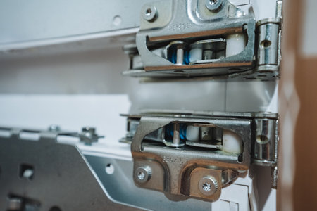 This text offers a detailed view of a durable metal hinge mechanism, highlighting its intricate structure and advanced engineering, commonly used in household appliances for smooth operationの写真素材