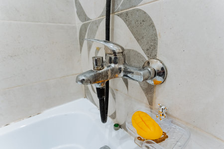 Sleek chrome bathroom faucet displayed against a stylish tiled wall, showcasing modern design and functionality for contemporary home interiorsの写真素材