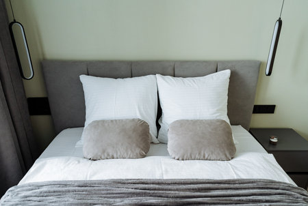 This elegantly designed bedroom features a chic gray headboard with soft white pillows and cozy blankets, creating a serene retreat perfect for relaxation and escaping daily stressesの写真素材