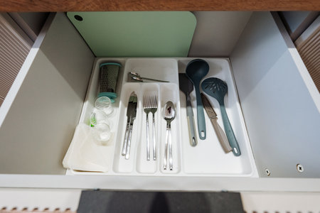 A neatly organized kitchen drawer, showcasing a diverse array of utensils, cutlery, and essential cooking tools, all set in a clean and minimalistic environment that exudes style and functionalityの写真素材