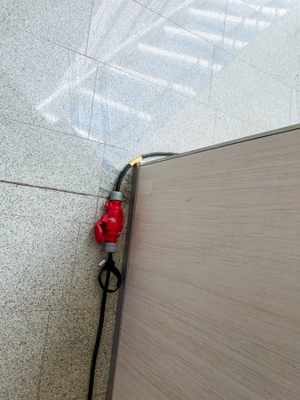 A red and black cord is attached to a wooden surface