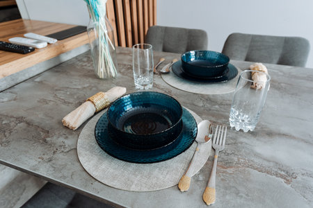 A beautifully arranged dining room table complete with various items like plates, bowls, glasses, and silverware, creating an inviting atmosphere for meals shared among family and friendsの写真素材