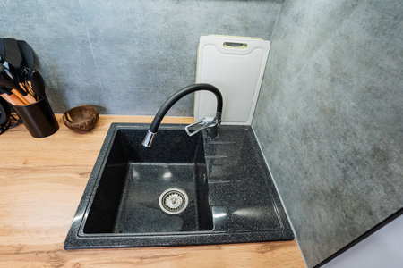 This modern kitchen sink features a stylish, efficient faucet and a handy cutting board, enhancing functionality and making food preparation simpler and more enjoyable for every home cookの写真素材