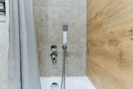 The bathroom features both a comfortable bathtub as well as a convenient shower head, providing users with multiple options for cleansing and relaxation during their bathing experienceの写真素材