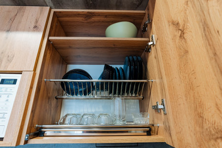 The inviting kitchen has a large, wellstocked cabinet with plates, glasses, and a decorative bowl, all organized for your convenience, perfect for cooking and entertaining guestsの写真素材
