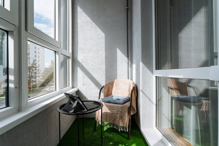 On the balcony of the apartment, there is a chair and a table set up, creating a cozy space to enjoy the outdoors and take in the views of the condominium and highrise buildings nearbyの写真素材