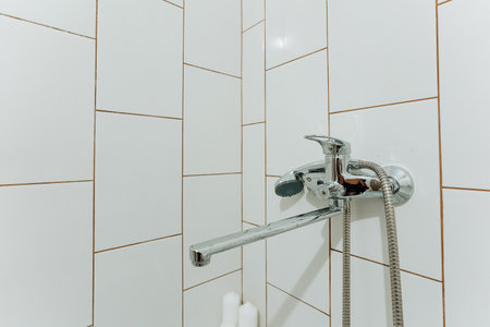 The bathroom features a stylish layout with white tiles and a modern shower head, enhancing hygiene and comfort, making it ideal for unwinding after a long day or preparing for the day aheadの写真素材