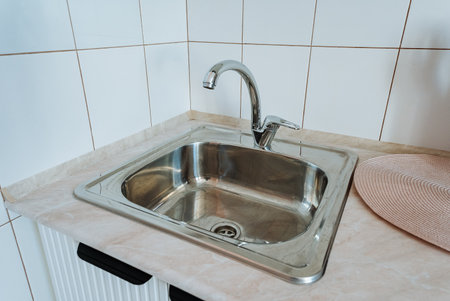 The kitchen boasts a polished stainless steel sink and a modern faucet on the countertop, enhancing functionality and visual appeal, making it an inviting space for cooking and socializingの写真素材