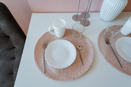 An elegantly set dining table with neatly arranged plates, shiny utensils, and a charming cup creates a warm atmosphere for enjoying a delightful meal with family or close friendsの写真素材
