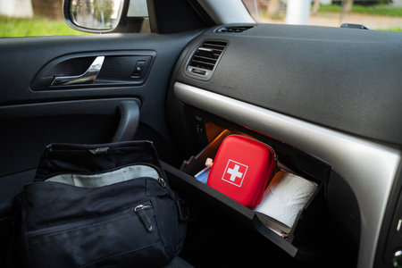 A well-arranged car interior showcasing a compact first aid kit in the glove compartment, with an elegant black bag placed nearby, perfect for road safety. Ideal for automotive content.の写真素材