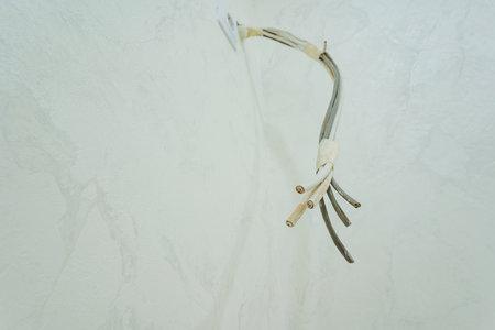 A collection of wires is notably hanging down from a pristine white wall, creating an intriguing visual contrast with the surrounding environment.の写真素材