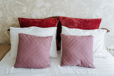 A beautifully arranged bed with plush pastel pillows and vibrant throws creates an inviting atmosphere for relaxation and comfort, making it an ideal retreat for unwinding and enjoying restの写真素材