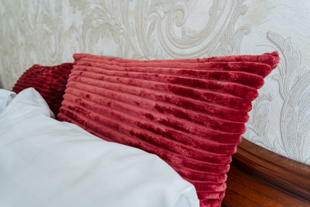 A vibrant red throw pillow rests on a serene bed with luxurious white linens, creating an inviting...