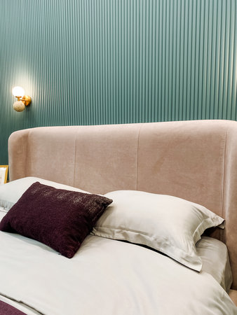 This beautifully designed bedroom has a plush headboard for comfort, decorative pillows, and soft...