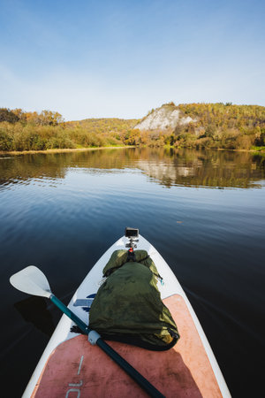 Enjoy a peaceful paddleboarding trip across a tranquil lake, surrounded by stunning autumn colors...