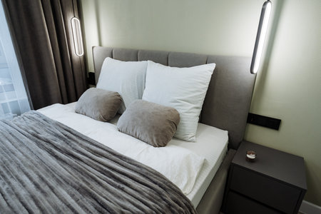 This stylish bedroom features a spacious queen bed with fluffy pillows and a modern nightstand. The...
