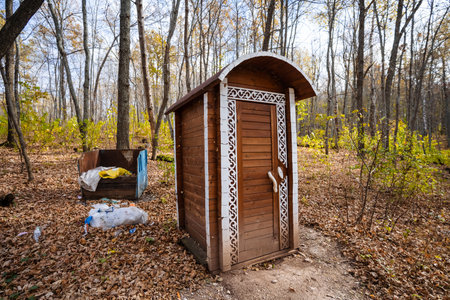 In the center of a serene and beautiful forest, a wooden outhouse is quietly sitting among the trees, surrounded by natures beauty and the vibrant colors of the foliage in autumnの写真素材
