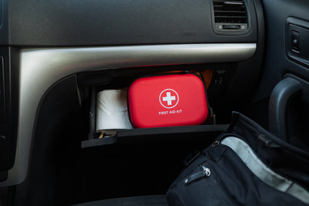 A compact red first aid kit, neatly stored in the glove compartment of a car, highlights the crucial...