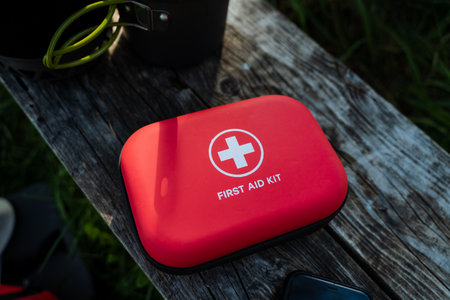 A bright red first aid kit, prominently displayed on rustic wood, is not only visually appealing but also an essential item for a variety of users engaged in outdoor activities and emergencies alikeの写真素材