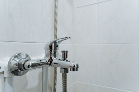 This image features a detailed closeup of a shower faucet situated in a bathroom environment, showing the elegant design of this essential household hardware and plumbing fixtureの写真素材