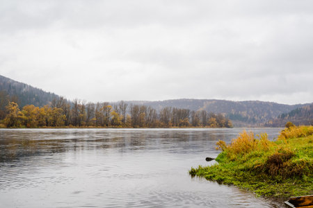 A tranquil river framed by vibrant autumn foliage and rolling hills, capturing natures essence on a...