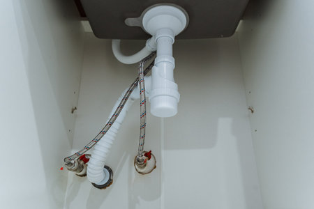 accessible plumbing features, accessible sink and plumbing setup, easily accessible sink plumbing with visible valves, undercabinet and exposed sink plumbing with accessible parts visiblyの写真素材
