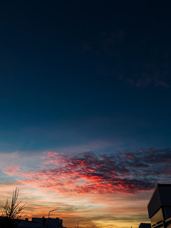 A breathtaking view of the evening sky showcasing vibrant sunset colors with scattered clouds against a deep blue background, perfect for nature and landscape photography enthusiasts.の写真素材