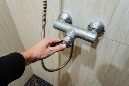 A hand adjusts a modern shower faucet, highlighting its innovative design and multifunctionality in a luxurious bathroom that combines comfort and stylish aesthetics for an upscale experienceの写真素材