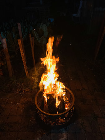 A vibrant fire dances joyfully in a beautifully decorative fire pit, casting a warm and inviting glow that creates a cozy and comforting atmosphere against the serene backdrop of nature all aroundの写真素材