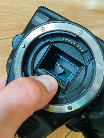 A closeup and detailed view of a camera, showing a user skillfully removing or adjusting the lens mount, which highlights the intricate and sophisticated mechanics behind photography equipmentの写真素材