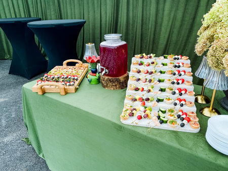 An exquisitely arranged catering table showcases a vibrant variety of colorful appetizers, enticing...